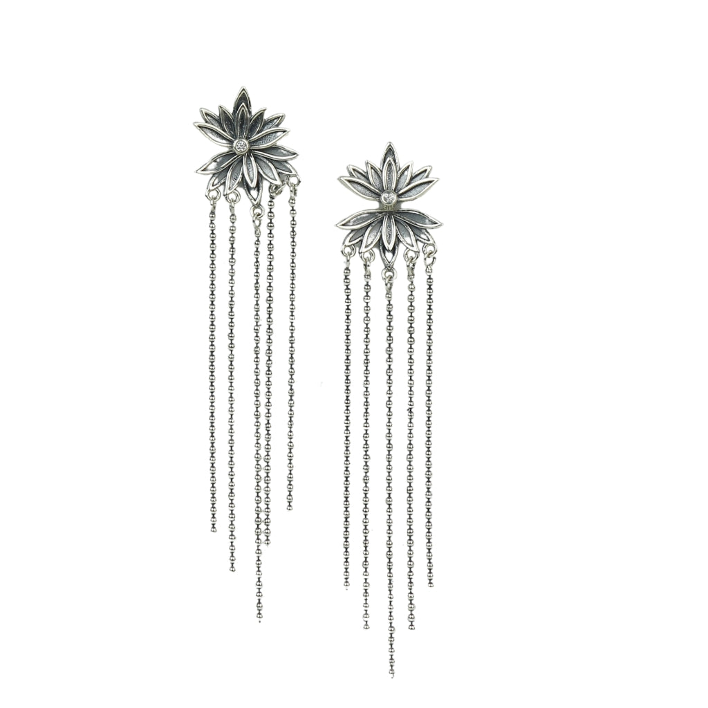 Pair of silver floral earrings with chain drops on a white background